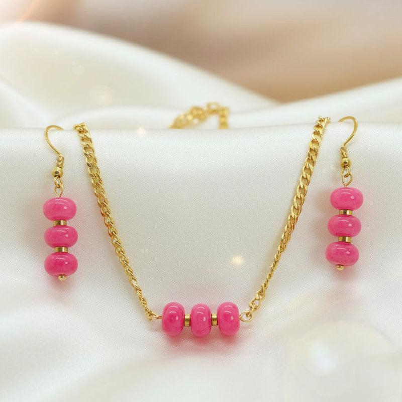Gold jewelry set featuring a necklace and matching drop earrings with pink beads, displayed on a white satin fabric background. The text 'Ethereal Glow Collection' is visible at the bottom.